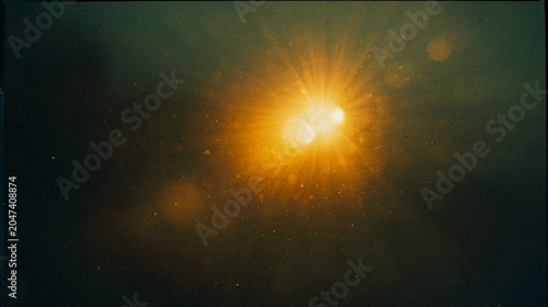 Abstract dark background with a brilliant golden sunburst light flare, cinematic glowing particles, vintage film grain texture, elegant moody atmosphere for luxury graphic design and commercial