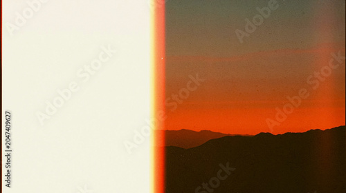 Abstract sunset gradient background with vintage film light leak and copy space, warm orange and cream colors, textured sky, silhouette mountains, ideal for wallpaper, backdrop, modern design,