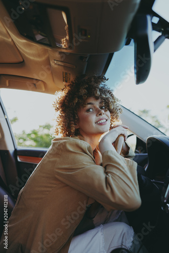 Foto Young woman sits in a car interior wearing a casual hoodie, warm daylight filter