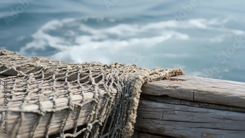 Weathered fishing net on wooden boat edge shown in slow motion macro detail for coastal industry documentary footage