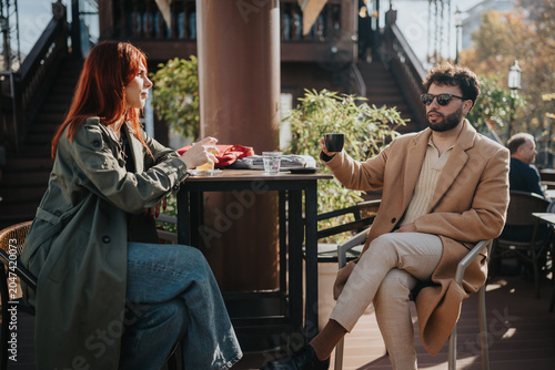 Valokuva Two colleagues sit at a cafe table outdoors, enjoying coffee and conversation during a casual meeting