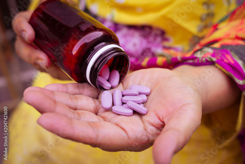 Cuadro en lienzo Hand holding open amber bottle dispensing purple oval tablets with medication ph