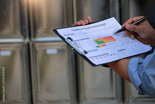 Foto Serious inspector holding chemical hazard assessment form with diligent concentr