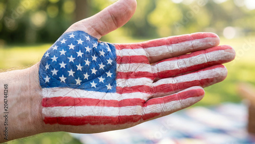 Palm displaying a painted American flag symbol sits open to represent freedom, democracy, and the core values of a patriotic nation.