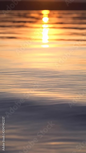 Golden hour sun reflection on calm rippling water.