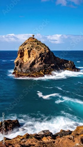 Rugged Volcanic Sea Stack Rising From Turquoise Ocean Waves on Sunny Coast
