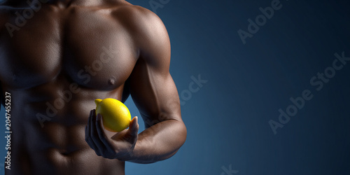 Muscular man holding lemon, showcasing strength and vitality against dark background