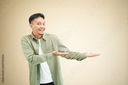 Canvas-taulu Happy young Asian man presenting with one open palm extended sideways toward cop