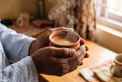South Asian hands cupping steaming clay kullad of chai, Indian lifestyle comfort and morning tea culture