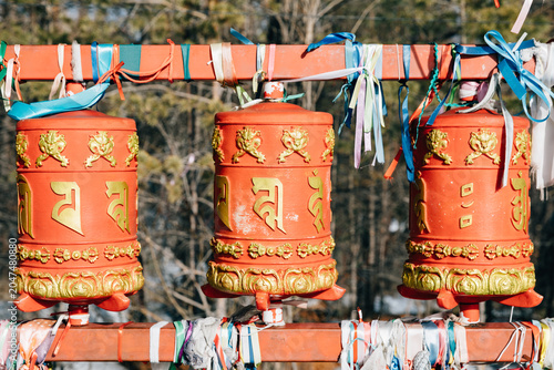 Photos Close-up of three red Tibetan Buddhist prayer wheels with golden script and colo