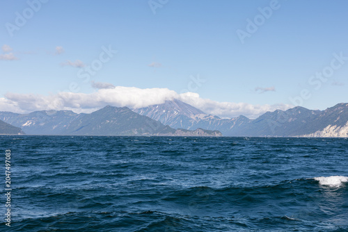 Quadro su tela Wide view of deep blue ocean with small waves and distant volcanic mountain rang