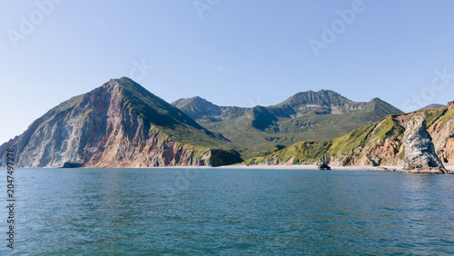 Foto Wide seascape view of rugged volcanic cliffs, green mountain ridges and calm blu