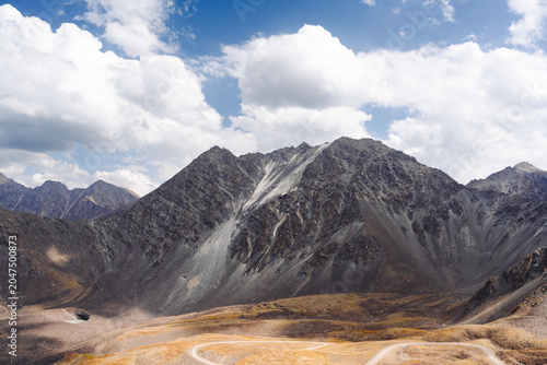 Slika na platnu Horizontal view of a winding dirt road leading through the mountains near Kegety pass, Kyrgyzstan