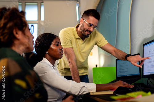 Three colleagues sitting together in a modern office, collaborating and working on computers.