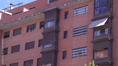 Modern residential apartment building featuring terracotta brick facade, balconies and contemporary urban housing architecture. Exterior architectural detail of a multi-story residential complex.