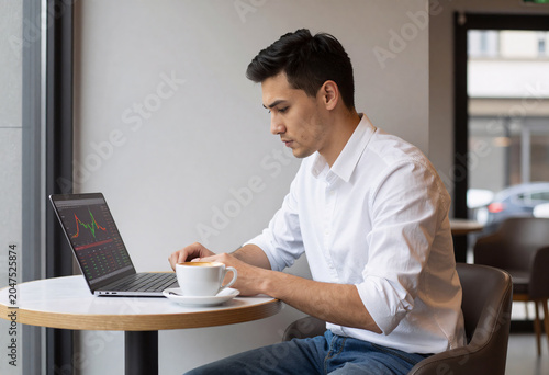 Entrepreneur checking stock market graphs in modern cafe