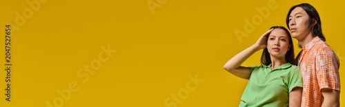 Fotografie Young couple shares a moment of love and style against a vibrant yellow backdrop