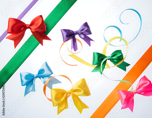 Vibrant satin ribbons and bows in a spectrum of bright colors, creating a festive and decorative arrangement on a clean background