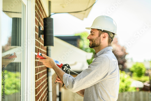 фотографія Construction worker uses sealant gun during window installation