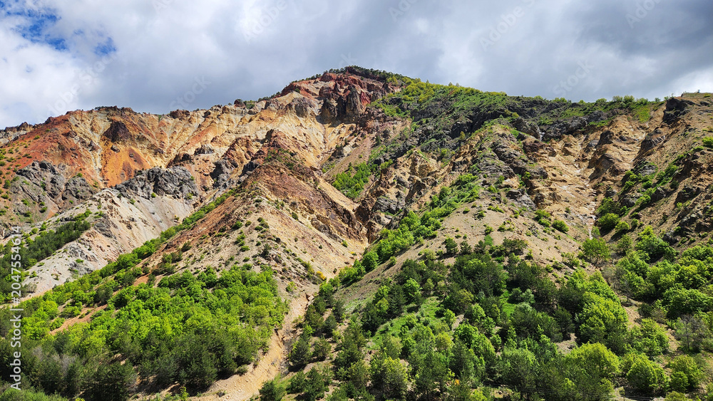 Obraz premium Rainbow Hills in Şebinkarahisar, Giresun, feature striking multicolored geological formations created by mineral-rich soils containing copper and gold, with a long history of mining in the region.