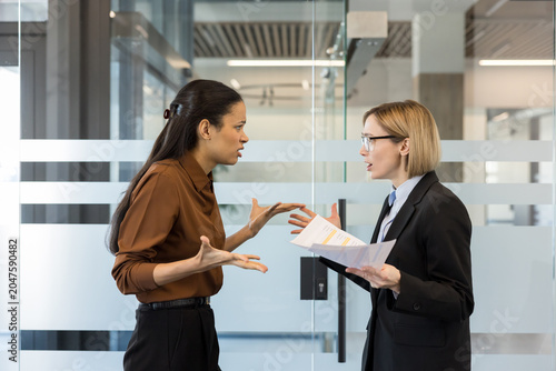 Vászonkép Two businesswomen argue over paperwork during a tense corporate meeting, showing