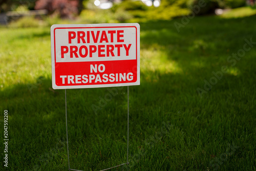 Foto "Private Property No Trespassing" sign placed outdoors on lawn to keep trespassers away from property line