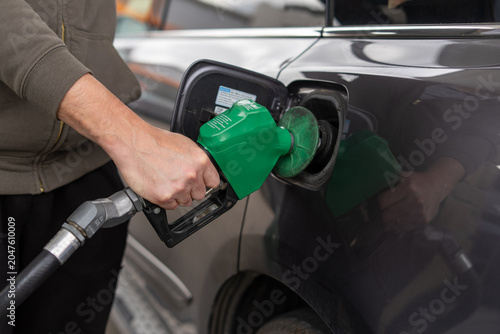 Photography Horizontal close up of person holding green fuel pump nozzle to refuel car tank