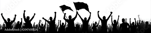 Silhouettes of cheering crowd raising hands and waving flags in celebration at large outdoor event with vibrant energy and unity