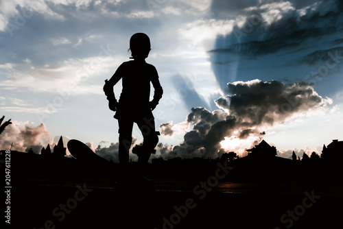 Silhouettes of people with a skateboard against the backdrop of a sunset, rays of sun breaking through the clouds