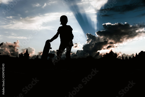 Silhouettes of people with a skateboard against the backdrop of a sunset, rays of sun breaking through the clouds