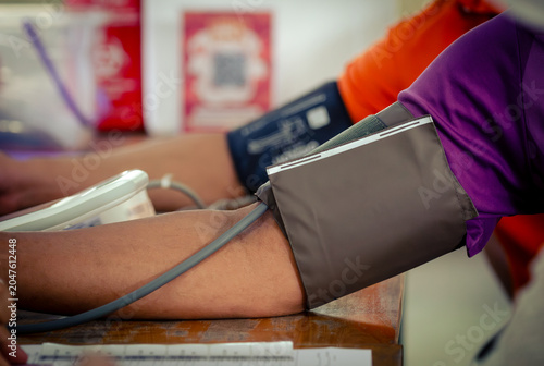 Annual checkup concept. Doctor is measuring patient's blood pressure. The patient has a blood pressure cuff on his arm.