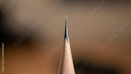 Sharp pencil tip macro close up, graphite lead point on wooden pencil, artistic drawing tool for creative writing and sketching projects