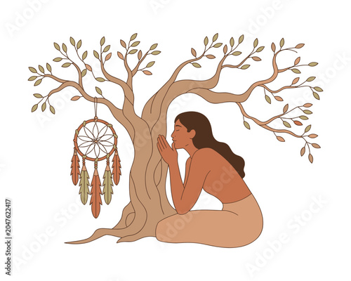 Woman sitting next to tree with dreamcatcher hanging from branch