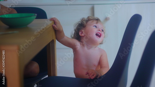 Bild auf Leinwand Upset toddler beside dining chair during family mealtime needing help and suppor