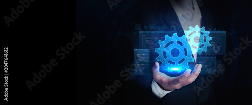 Digital Gears of Progress: A person's hand, adorned in a suit, delicately holds glowing blue digital gears, symbolizing innovation and the interconnectedness of technology and business.