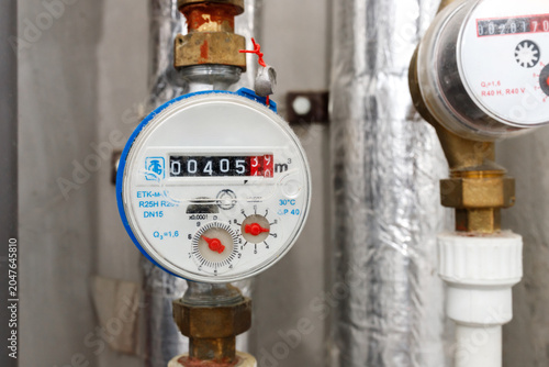 Foto Water meters counter on pipes inside residential utility room infrastructure or