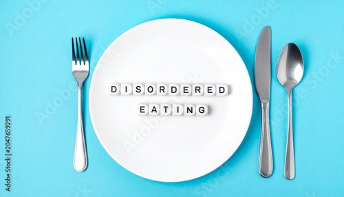 Concept of Disordered Eating Spelled Out on Dinner Plate with Fork and Knife