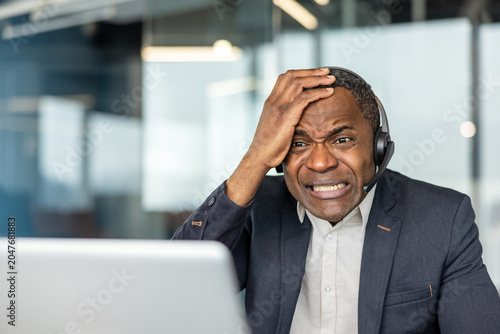 Foto Frustrated mature employee wearing a headset and suit holding his head, experien