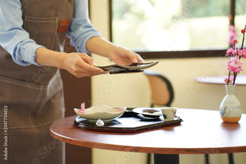 Canvas-taulu A staff member carefully sets down a tray with food and drinks for a customer at a table