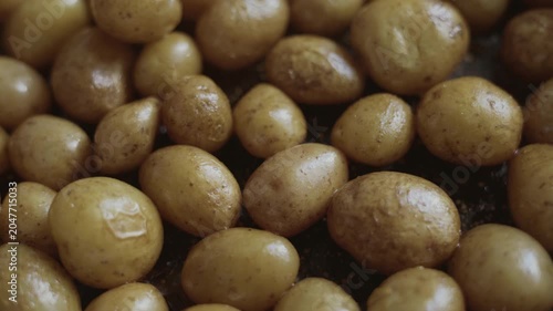 Whole potatoes are fried in oil in a kitchen pan