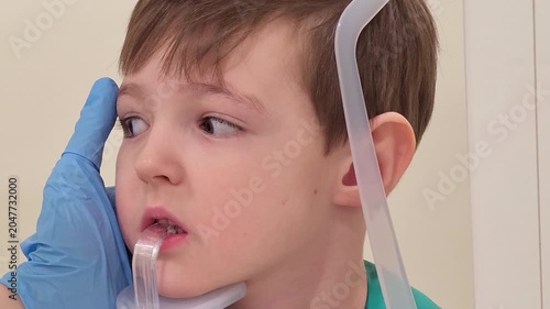 Child patient stands at dental x-ray machine for panoramic skull scan. Professional dentist holding boy head of young patient during medical diagnostic exam. Pediatric clinic concept.