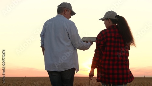 Valokuva rural partnership: handshake over ripening grain, woman assists man farmer operating tablet in dense wheat field