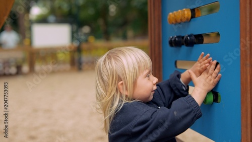 Brighthaired kid examines tactile shapes during outdoor activity