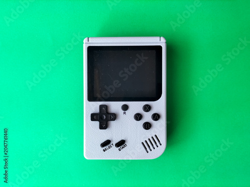 Retro handheld gaming console on a green background.