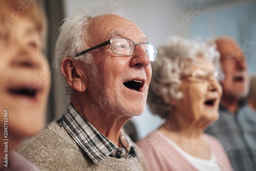 Elderly people singing together with joy and emotion in a group activity