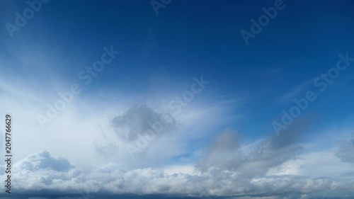 Dark storm cloud gathering in blue sky, time lapse. Ominous weather conditions with heavy rain clouds before thunderstorm. Atmospheric nature background for climate change and meteorology concept.