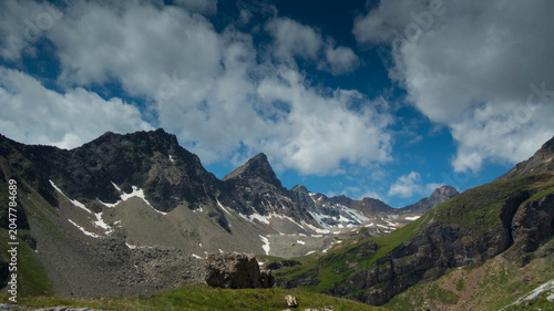 Majestic rocky mountain peaks under a dramatic blue sky with fast-moving white clouds, high alpine landscape in the Loetschental valley, Valais, Switzerland.