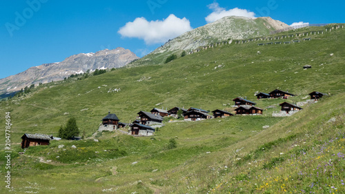 Beautiful alpine village with traditional dark wooden chalets and a small chapel on a green hill in Lauchernalp, Loetschental valley, Valais, Switzerland.