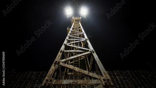 Low angle view of a tall metal lighting tower at night.