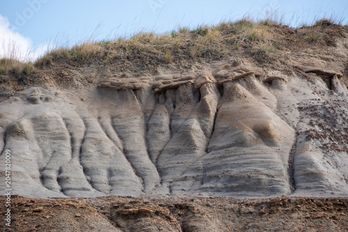 Obraz na plátně Severe soil erosion on a badlands hillside with a grassy peak